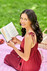 Image showing happy woman reading book at picnic in summer park