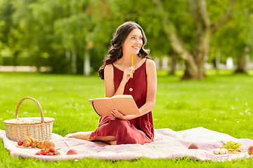 Image showing happy woman with diary and picnic basket at park