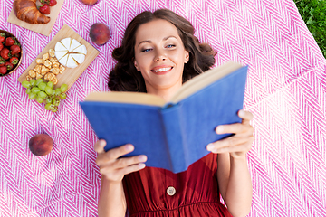 Image showing happy woman reading book at picnic in summer park
