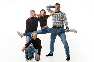 Image showing Dad and son hold their daughter on a stretch, the second son sits next to him, full-length portrait, white background