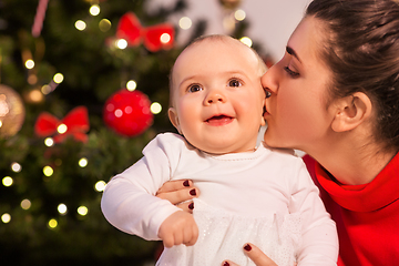 Image showing mother kissing baby daughter over christmas tree