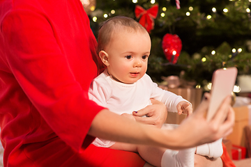 Image showing mother with baby girl and smartphone on christmas