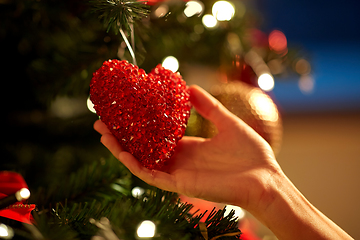 Image showing hands decorating christmas tree with red heart