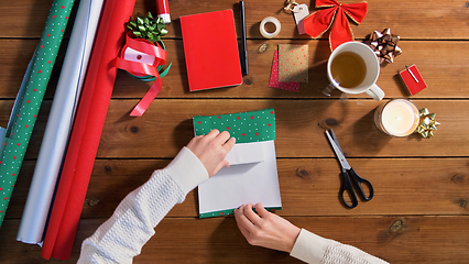Image showing hands wrapping christmas gift into paper at home