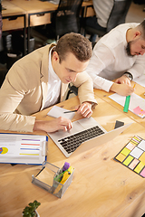 Image showing Young caucasian colleagues working together in a office using modern devices and gadgets