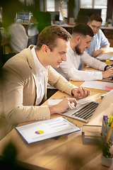 Image showing Young caucasian colleagues working together in a office using modern devices and gadgets