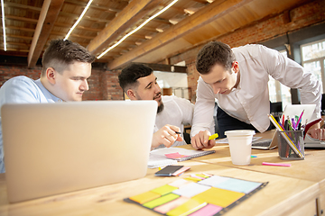 Image showing Young caucasian colleagues working together in a office using modern devices and gadgets