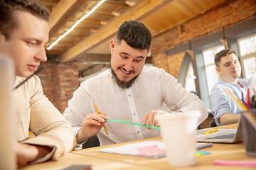 Image showing Young caucasian colleagues working together in a office using modern devices and gadgets