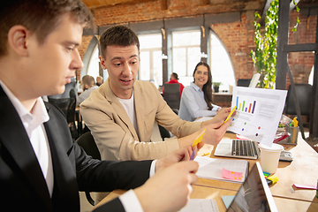 Image showing Young caucasian colleagues working together in a office using modern devices and gadgets