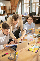 Image showing Young caucasian colleagues working together in a office using modern devices and gadgets