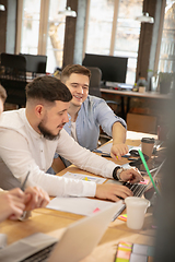 Image showing Young caucasian colleagues working together in a office using modern devices and gadgets