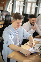 Image showing Young caucasian colleagues working together in a office using modern devices and gadgets