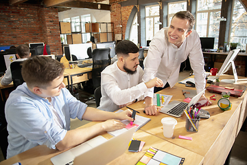 Image showing Young caucasian colleagues working together in a office using modern devices and gadgets