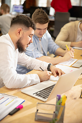 Image showing Young caucasian colleagues working together in a office using modern devices and gadgets