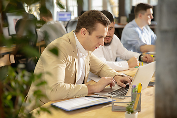 Image showing Young caucasian colleagues working together in a office using modern devices and gadgets