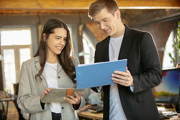 Image showing Young caucasian colleagues working together in a office using modern devices and gadgets