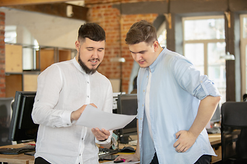 Image showing Young caucasian colleagues working together in a office using modern devices and gadgets