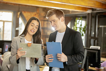 Image showing Young caucasian colleagues working together in a office using modern devices and gadgets