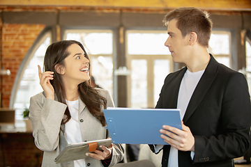 Image showing Young caucasian colleagues working together in a office using modern devices and gadgets