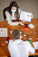 Image showing High angle view colleagues working together in face masks during quarantine in a office using modern devices and gadgets during creative meeting