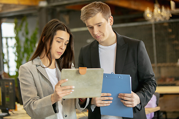 Image showing Young caucasian colleagues working together in a office using modern devices and gadgets