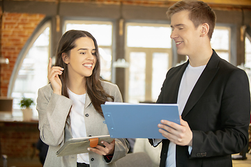 Image showing Young caucasian colleagues working together in a office using modern devices and gadgets