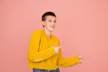 Image showing Caucasian girl\'s portrait isolated on coral pink studio background with copyspace