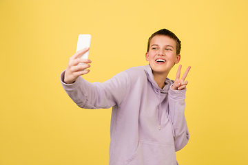 Image showing Caucasian girl\'s portrait isolated on yellow studio background with copyspace