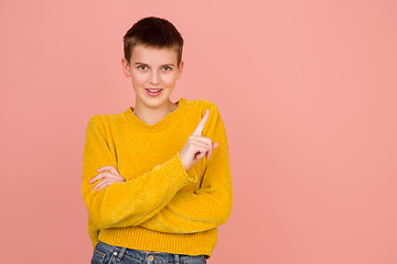 Image showing Caucasian girl\'s portrait isolated on coral pink studio background with copyspace