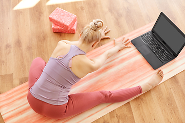 Image showing woman with laptop exercising at yoga studio
