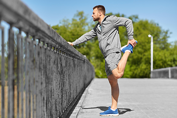 Image showing man stretching leg on bridge