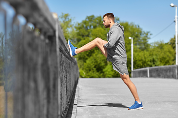 Image showing man stretching leg on bridge