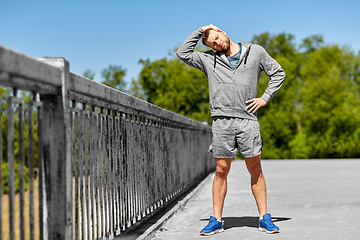 Image showing man stretching neck on bridge