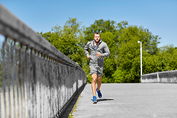 Image showing happy young man running across city bridge