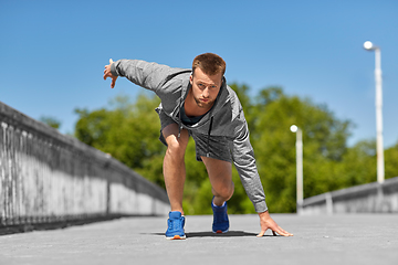 Image showing young man running across city bridge