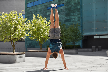 Image showing young man exercising and doing handstand outdoors