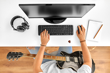 Image showing young man with computer and guitar at table