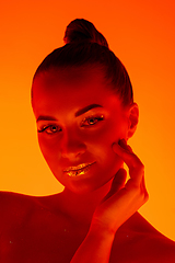 Image showing Handsome woman\'s portrait isolated on orange gradient studio background in neon light, monochrome