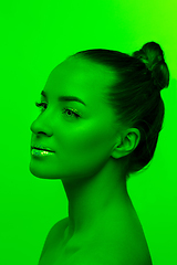 Image showing Handsome woman\'s portrait isolated on green studio background in neon light, monochrome