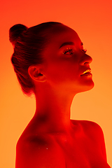 Image showing Handsome woman\'s portrait isolated on orange gradient studio background in neon light, monochrome