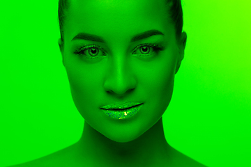 Image showing Handsome woman\'s portrait isolated on green studio background in neon light, monochrome