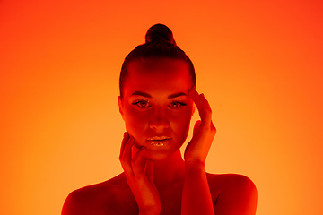 Image showing Handsome woman\'s portrait isolated on orange gradient studio background in neon light, monochrome