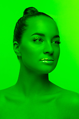 Image showing Handsome woman\'s portrait isolated on green studio background in neon light, monochrome