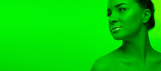 Image showing Handsome woman\'s portrait isolated on green studio background in neon light, monochrome