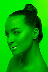 Image showing Handsome woman\'s portrait isolated on green studio background in neon light, monochrome