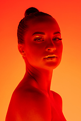 Image showing Handsome woman\'s portrait isolated on orange gradient studio background in neon light, monochrome