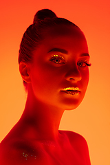 Image showing Handsome woman\'s portrait isolated on orange gradient studio background in neon light, monochrome