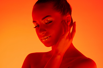 Image showing Handsome woman\'s portrait isolated on orange gradient studio background in neon light, monochrome