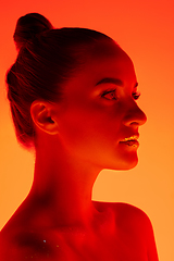 Image showing Handsome woman\'s portrait isolated on orange gradient studio background in neon light, monochrome