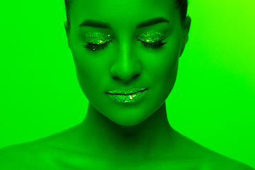 Image showing Handsome woman\'s portrait isolated on green studio background in neon light, monochrome